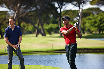 Image showing Man, friends and swing of golfer with club on grass field by lake for stroke, score or point in outdoor competition. Male person or people hitting ball to hole, target or par on golf course in nature