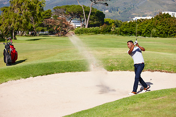 Image showing Man, golfer and swing with stroke in sand pit for par, bogey or strike with grass field in nature. Young male person or sports player hitting ball out for point or tough outdoor shot on golf course