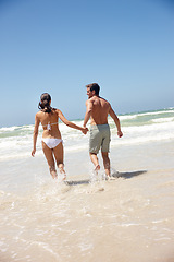 Image showing Couple, rear view and holding hands in water with travel for bonding, summer vacation and anniversary getaway. Man, woman and love by ocean with swimwear for walking, healthy relationship or blue sky