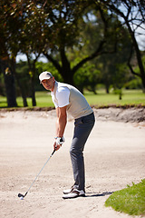 Image showing Man, portrait and golfer with club for stroke, point or strike in sand pit by grass field in nature. Male person or sports player getting ready to swing ball in dirt for game or match on golf course