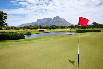 Image showing Flag, hole and grass at golf course in landscape of summer on luxury holiday or vacation. Calm, morning and lawn with turf on field for sport in woods, forest or goal in park with trees and clouds