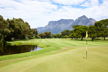 Image showing Hole, flag and grass at golf course in landscape of summer on luxury holiday or vacation. Calm, morning and lawn with turf for sport in woods, forest or nature of park with water, trees and field