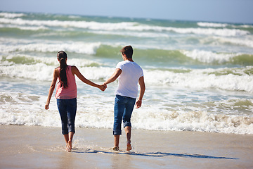 Image showing Couple, holding hands and beach with back for love, support or care together on outdoor holiday. Rear view of man and woman enjoying fun walk or playing on the ocean coast, water or bonding in nature