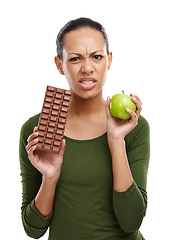 Image showing Portrait, woman and choosing chocolate versus apple for health, wellness and diet benefits. Thinking, person and choice of candy, fruits and healthy food challenge for nutritional balance in studio