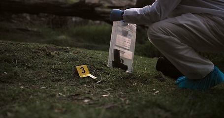 Image showing Crime scene, gun and investigator with evidence outdoor for forensics, analysis and investigation in forest or nature. Person hands with weapon, ppe and inspection or police search for clues in woods