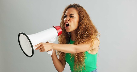 Image showing Angry woman, shouting and protest with megaphone for power, rights or equality on a gray studio background. Frustrated female person or activist screaming with fist and bullhorn for announcement