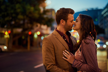 Image showing Couple, night and city street with hug and kiss on date, romance and bonding with love in relationship. Affection, people with commitment and trust, sweet moment and romantic together outdoor