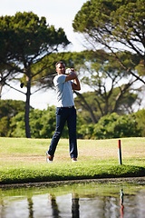 Image showing Man, golfer and swing with club on grass field by the lake for point, score or par in outdoor nature. Male person or sports player hitting ball away on green lawn or golf course by water or pond