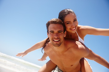 Image showing Happy, portrait and couple flying with piggy back at the beach with love and support on holiday in summer. Laugh, sea and vacation with smile and bonding by water with travel in Miami with people