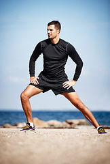 Image showing Man, stretching and ocean on sand with shoes for health, fitness and exercise by beach for peace and calm. Athlete, yoga and sea in morning for wellness, motivation and workout or training by nature