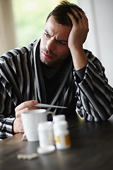 Image showing Man, sad and sick with headache, thermometer for fever with sinus or virus at home. Health fail, medication or pills for flu or cold, monitor condition for allergies and viral infection with medicine