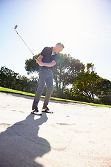 Image showing Man, golfer and swing with club in sand pit by grass field for point, score or par in outdoor nature. Male person or sports player hitting ball out of dirt on green lawn or golf course with blue sky