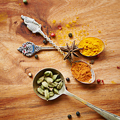 Image showing Spoons, spice and selection of cuisine for seasoning on kitchen table, turmeric and cardamom for meal. Top view, condiments and options for spicy cooking in Indian culture, cumin and food preparation