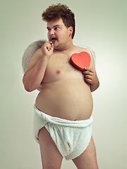 Image showing Man, cupid and heart with costume in studio for wings, bow and arrow on isolated gray background. Fantasy, chocolate and plus size male model for character role play, creative dress up or cosplay