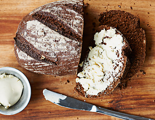 Image showing Sourdough, bread and butter on slice for food, nutrition and carbs on kitchen table or fibre. Top view, wheat and rye snack on wooden board, grain and organic ingredients for artisan meal in home