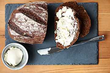 Image showing Sourdough, bread and butter on slice for cooking, nutrition and carbs on kitchen table or fibre. Top view, wheat and rye snack on wooden board, grain and organic ingredients for artisan meal in home