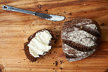 Image showing Sourdough, bread and butter on slice for meal, nutrition and carbs on kitchen table or fibre. Top view, wheat and rye snack on cutting board, grain and organic ingredients for artisan food in home