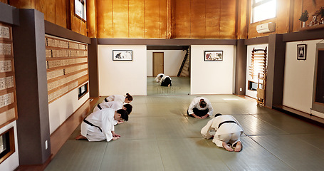 Image showing Aikido class, group and students of martial arts, bow and respect with calm at training, gym dojo. Japanese people, black belt and club for exercise, workout or fitness with fight, conflict or battle