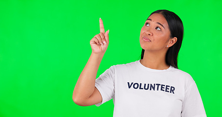 Image showing Volunteer, green screen and a woman pointing at space for advertising, charity or information. Face of happy asian person with a hand and tshirt for nonprofit project, NGO help or donation in studio