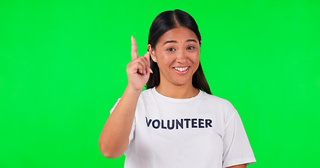 Image showing Volunteer, green screen and a woman pointing at space for advertising, charity or information. Face of happy asian person with a hand and tshirt for nonprofit project, NGO help or donation in studio