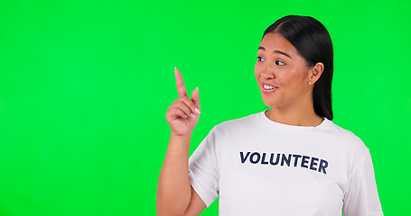 Image showing Volunteer, green screen and a woman pointing at space for advertising, charity or information. Face of happy asian person with a hand and tshirt for nonprofit project, NGO help or donation in studio