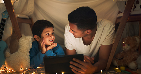 Image showing Night, father and boy on tablet in tent watching movies, online games and cartoon by blanket. Family, happy and dad with son and fairy lights in bedroom on digital tech for bonding, relax and love