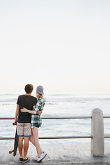 Image showing Couple, rear view and hug on beach for travel with mockup space, adventure and promenade date. Gen z skater, people and skateboard on boardwalk for bonding, embrace and outdoor fun with morning waves