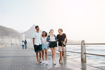 Image showing Group, friends and walk on promenade by ocean with smile for diversity, bonding and space for mockup. Men, women or gen z people with conversation, happy and outdoor on boardwalk by sea for vacation