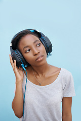 Image showing Thinking, music and black woman with headphones in city for sound, track or listening to podcast on blue background. Streaming, earphones or gen z student outdoor with radio, playlist or audio ebook