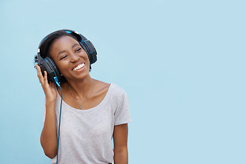 Image showing Happy, music and black woman with earphones in studio for streaming, sound or podcast on blue background. Remember, smile and gen z student with earphones, reflection or idea, hearing or radio news