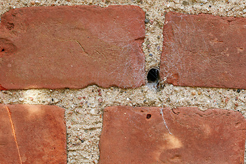 Image showing Building, hole and closeup of red, brick wall for texture, background and pattern of exterior structure. Architecture design, construction and surface of material, concrete and cement for decoration