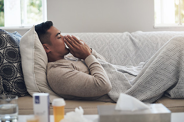 Image showing Sick, man and blowing nose with tissue for flu, sinus or illness on living room sofa at home. Tired male person with paper or medication for sneeze, fever or influenza and infection on couch at house