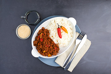 Image showing Mince, chili and rice for plate on dark background with Mexican menu, cutlery and healthy dinner. Chili con carne, starch and countertop in kitchen for nutrition, restaurant eating and comfort food