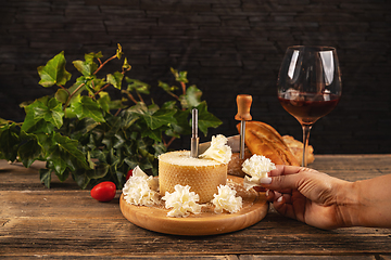 Image showing Woman slicing delicious tete de moine cheese