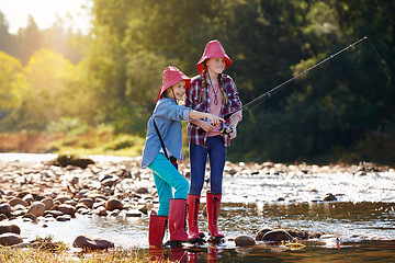 Image showing Countryside, activity and children fishing in river on holiday break, vacation or adventure as hobby. Sunshine, girls or siblings and rod to catch fish in water on weekend trip, outdoor and nature