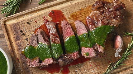 Image showing freshly grilled sliced steak with green parsley sauce