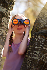 Image showing Tree, girl and binoculars for safari, search and looking for animals on travel holiday. Smile, fun and seek for bird watching or wildlife in nature, happy young child and scenery or view in Kenya