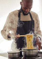 Image showing Man, cooking noodles and pot with steam at home for lunch or dinner, busy and hungry for food with preparation. Catering, African chef with chopsticks for Asian cuisine and nutrition in kitchen