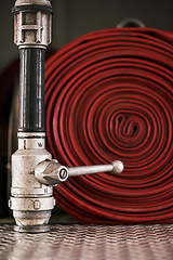 Image showing Emergency, equipment and pipe with red fire hose for security, danger or health and safety at station. Closeup of gear, tool or pressure extingusher ready in rescue, service or firefighting operation