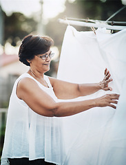 Image showing Mature woman, clothesline and laundry outdoor with household domestic chores, spring cleaning and housekeeping. Hanging clothes, fabric or white cotton sheet, cleaner and housework with washing