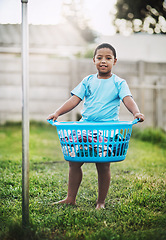 Image showing Boy, kid and outdoor with basket with clothes for growth, child development and learning. Portrait, happy and smile at home with washing or laundry for childhood memories, fun and house activity