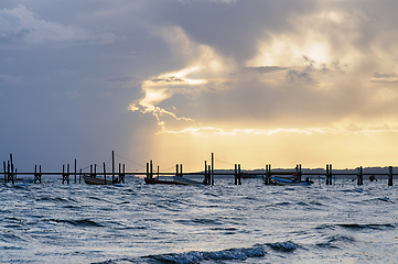 Image showing Serene Sunset Over Calm Waters With Fishing Boats and Stilted Do