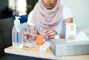 Image showing Muslim, woman and sick with pills on sofa in living room with illness, flu and tired at home. Female person, lounge and fever with medication to relax, chill and calm on couch for recovery or rest