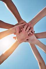 Image showing People, team and hands together below for unity, collaboration or synergy on a blue sky background. Closeup or low angle of group or community piling or stacking in solidarity for join or mission