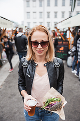 Image showing Beautiful young woman holding delicious organic salmon vegetarian burger and homebrewed IPA beer on open air beer an burger urban street food festival in Ljubljana, Slovenia.