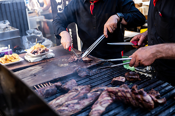 Image showing Some excellent pieces of Argentinian beef on a charcoal grill being prepared at open kitchen street food festival in Ljubljana, Slovenia.