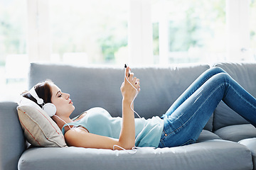 Image showing Girl, headphones and phone on sofa in house for music, relax and self care while on study break. Woman, headset and smartphone on couch in home living room for social media, video and app or radio