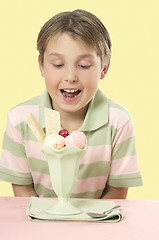 Image showing Child looking at an ice cream sundae on a table.