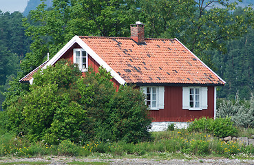 Image showing Small, red house among trees