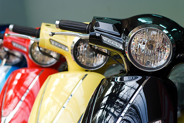 Image showing Three scooters, black, yellow and red
